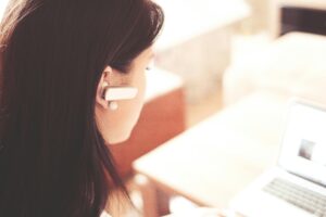 イヤホンをつけてパソコンで問い合わせ対応をする女性